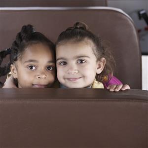 Two girls looking over the seat of a bus 